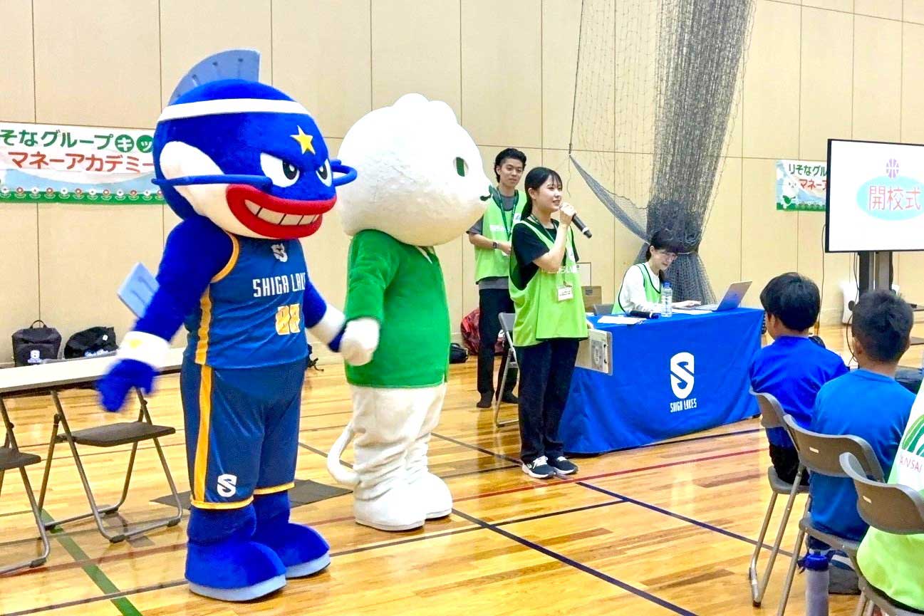 滋賀会場で、りそなグループのキャラクター「りそにゃ」と滋賀レイクスターズのキャラクター「マグニ―」が開港式に参加している写真
