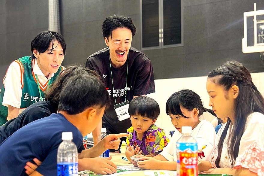 選手と子ども達が人生やりくりゲームを楽しむ様子
