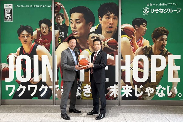 Bリーグの島田チェアマンとりそなホールディングス社長の南が一つのボールを中心に左右に立って一緒に持っている写真。