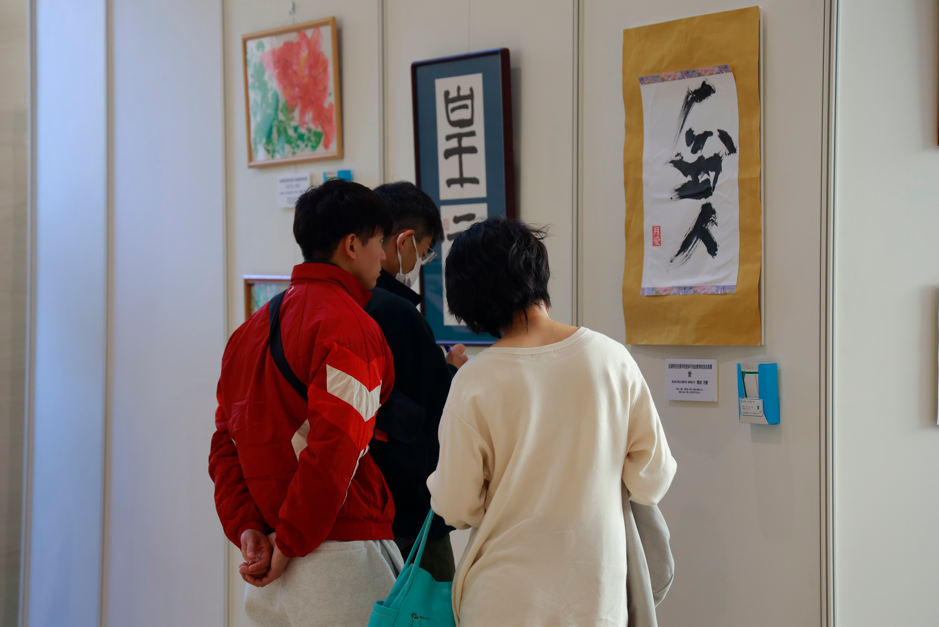 壁に掛けられた受賞作品を3人で見ている様子