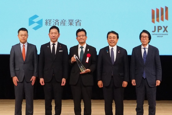 SX銘柄2026表彰式にて、伊佐グループCFOがトロフィーを受け取り、関係者と記念撮影している様子